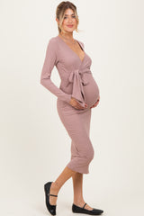 woman wearing a mauve long sleeve maternity dress with a tie waist and showing her baby bump