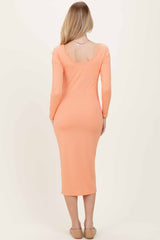 woman wearing a soft orange ribbed long sleeve midi dress with a scoop back