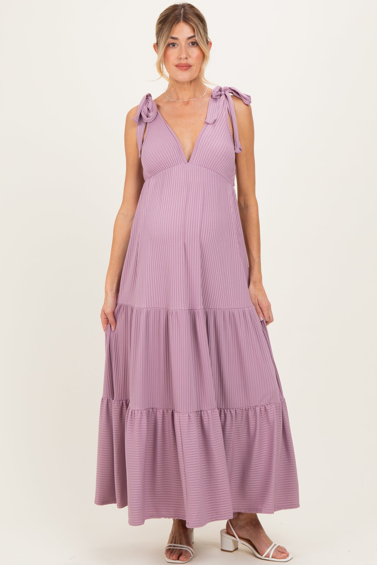 woman wearing a lilac maternity dress with adjustable tie straps and tiered skirt, showing her baby bump