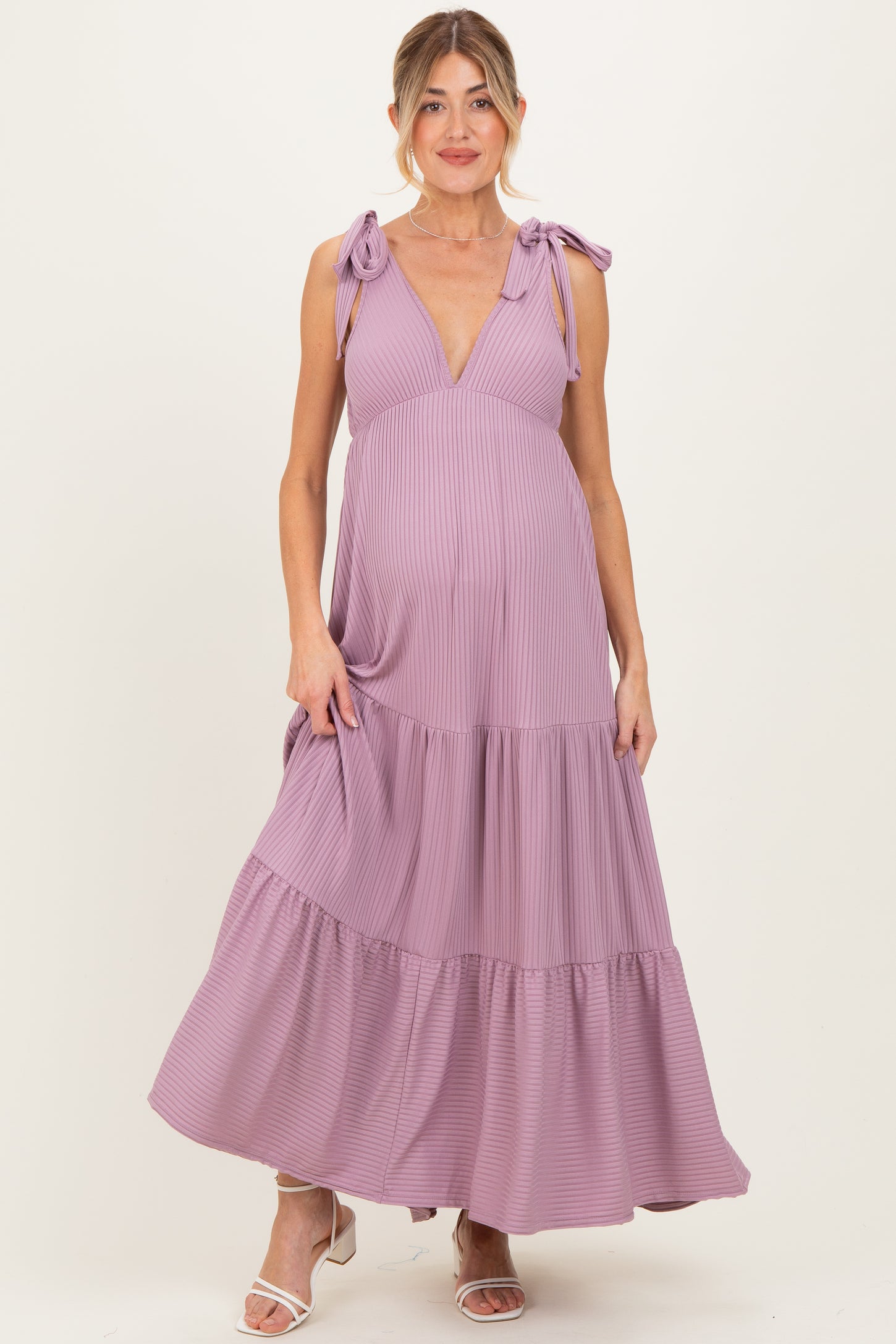 woman wearing a lavender striped maternity maxi dress with tie straps and a flowing tiered skirt, showing her baby bump
