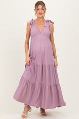 woman wearing a lavender striped maternity maxi dress with tie straps and a flowing tiered skirt, showing her baby bump