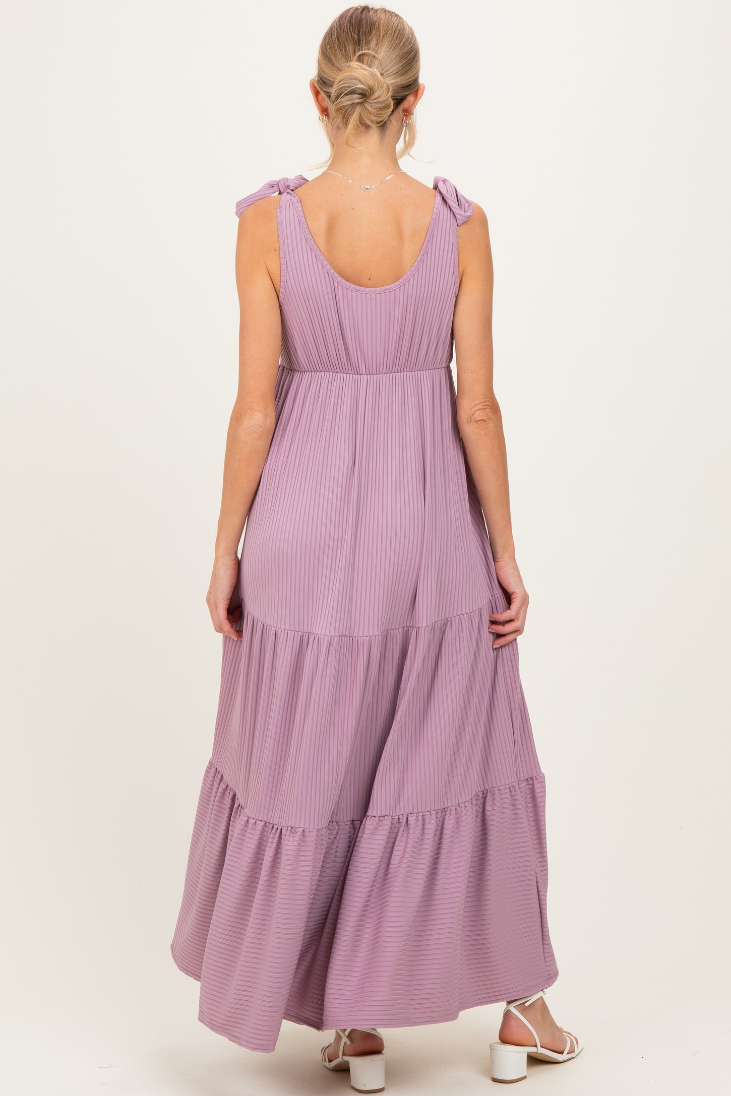 woman wearing a lavender maternity maxi dress with tie straps and tiered ruffles from the back