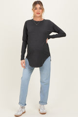 woman wearing a dark gray maternity long sleeve top and light blue jeans, showing her baby bump