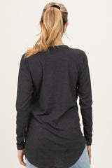 woman wearing a dark gray long sleeve maternity top with a curved hem, viewed from the back