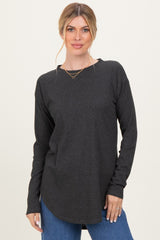 woman wearing a dark gray long sleeve top with a rounded hem and relaxed fit, paired with blue jeans