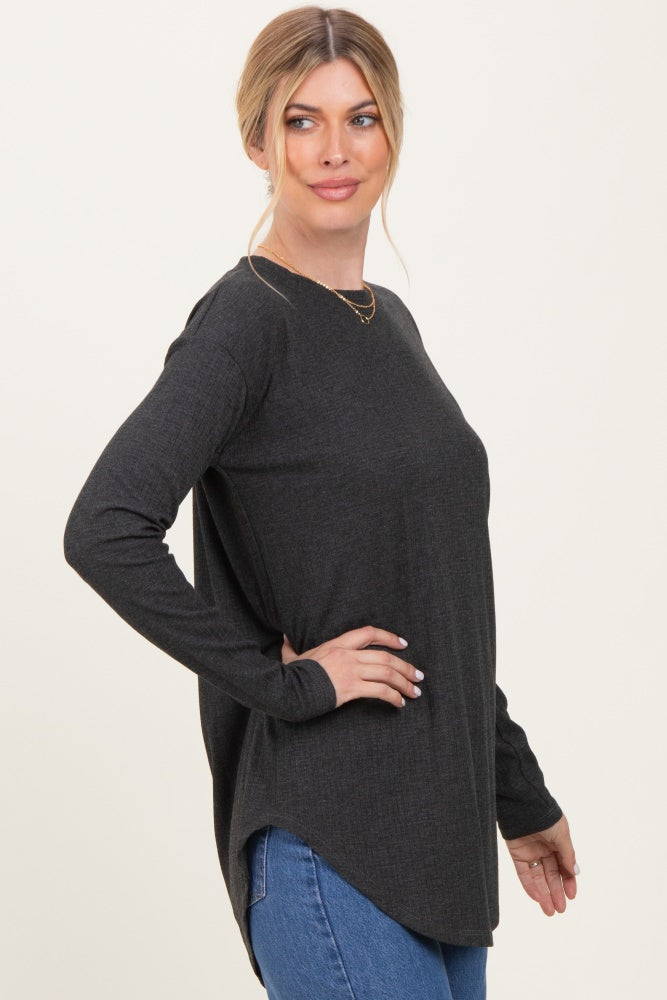 woman wearing a dark gray long sleeve top with a curved hem and side slits, styled with blue jeans