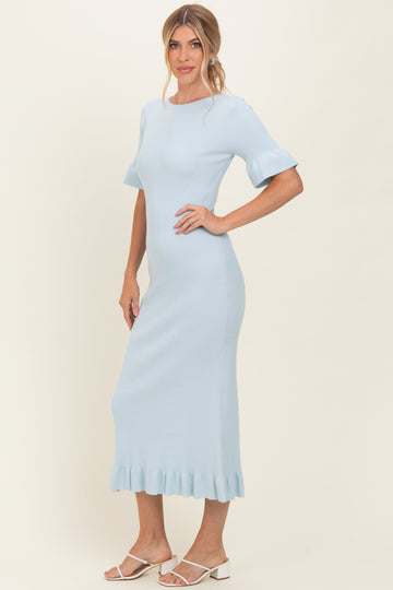 woman wearing a light blue ribbed midi dress with flared sleeves and a ruffled hem, standing against a neutral background