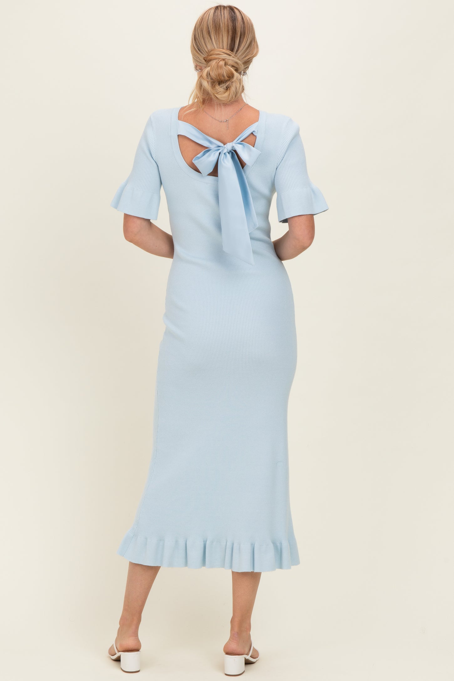 woman wearing a light blue ribbed midi dress with short sleeves and a tie detail at the back