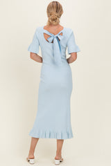 woman wearing a light blue ribbed midi dress with short sleeves and a tie detail at the back