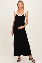woman wearing a black maternity maxi dress with white tie straps and holding her baby bump