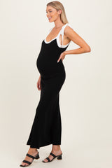 woman wearing a black maternity maxi dress with white accents and a visible baby bump