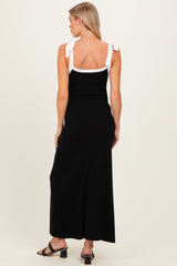 woman wearing a black maternity maxi dress with white bow shoulder straps and a fitted silhouette