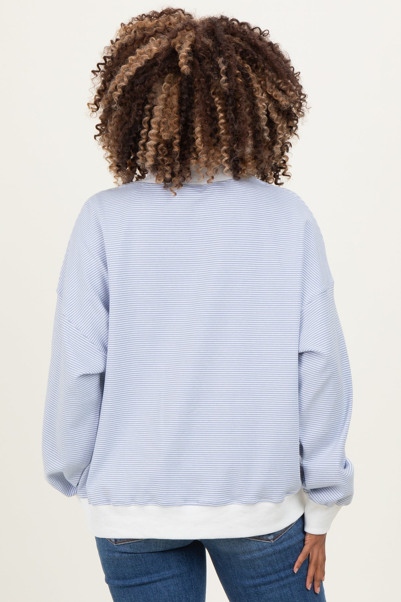 woman wearing a light blue striped maternity sweatshirt with a relaxed fit and white hem, shown from the back