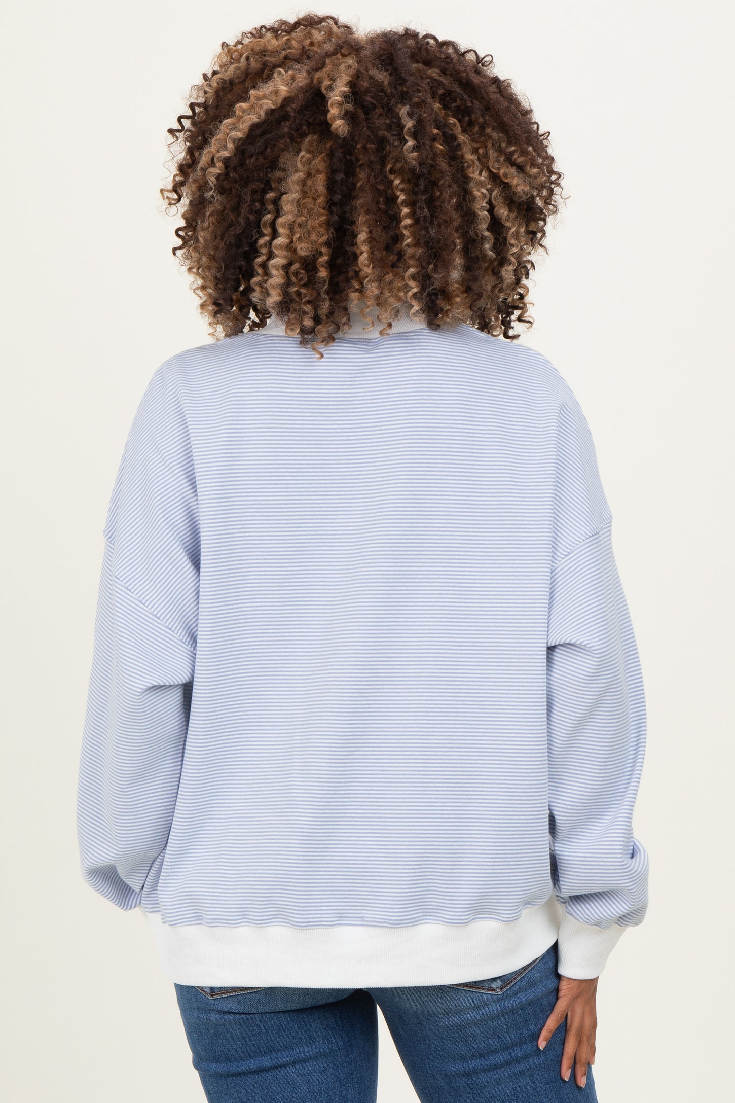 woman wearing a light blue striped maternity sweatshirt with a relaxed fit and white hem, shown from the back