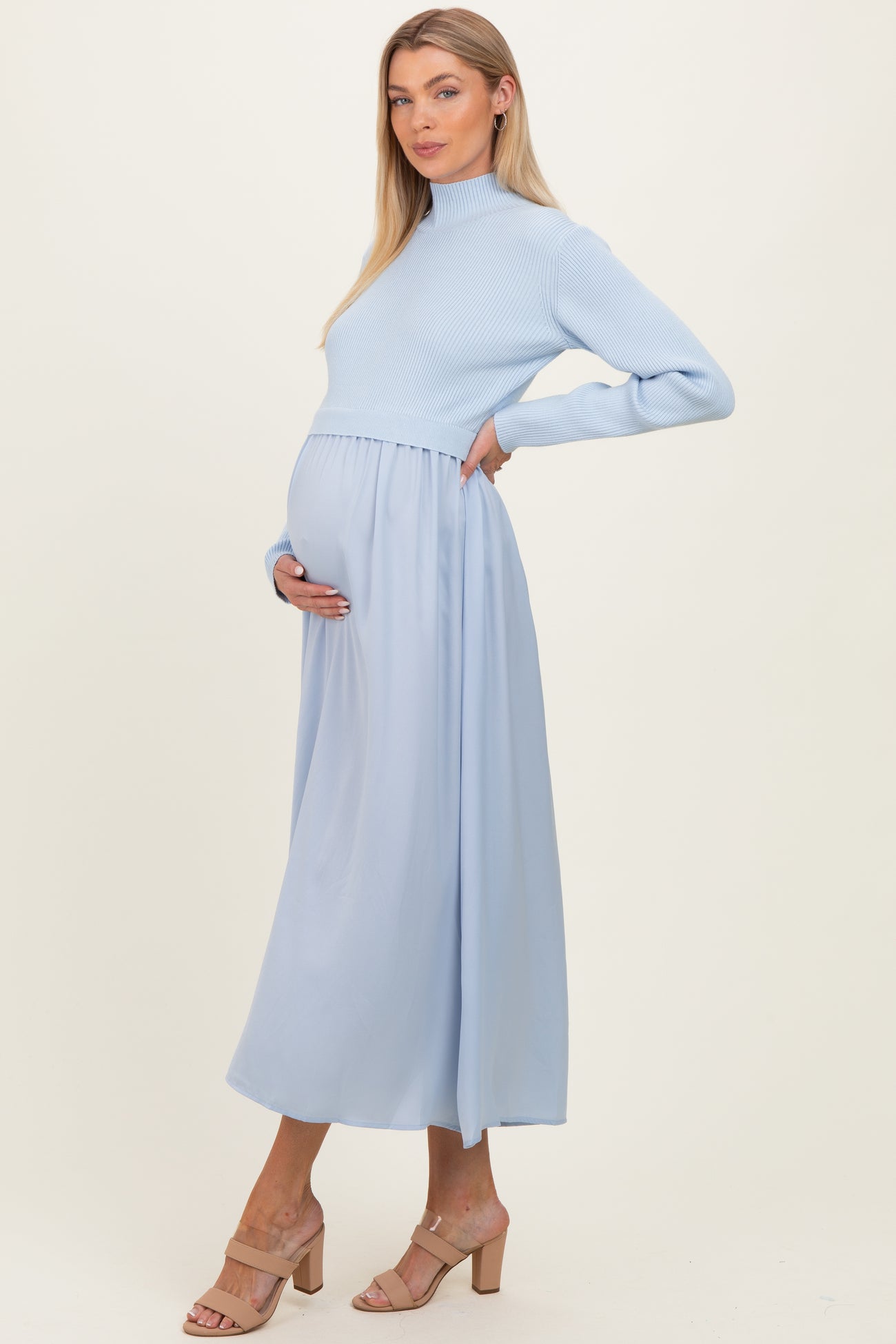 woman wearing a light blue maternity dress with a fitted ribbed top and flowing skirt, showcasing her baby bump