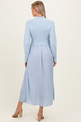 woman wearing a light blue maternity dress with a ribbed top and flowing skirt, back view, showcasing a baby bump
