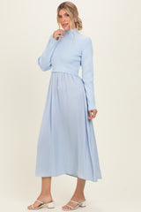 woman wearing a light blue mock neck knit top with a flowy maxi skirt in the same color