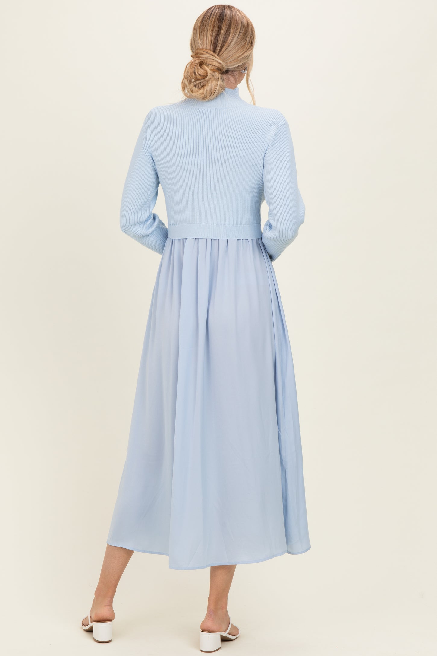 woman wearing a light blue ribbed knit long sleeve dress with a flowing chiffon skirt, viewed from the back