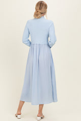 woman wearing a light blue ribbed knit long sleeve dress with a flowing chiffon skirt, viewed from the back