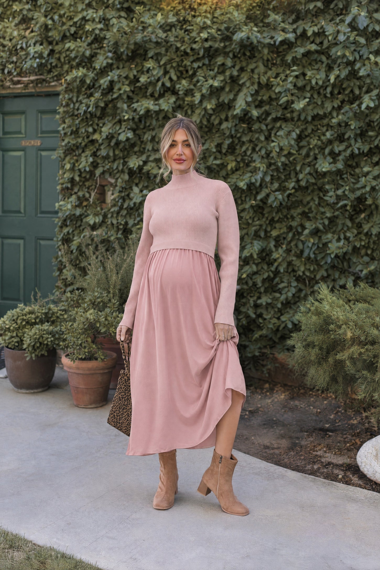 woman wearing a light pink long sleeve maternity dress with a ruffled hem and a visible baby bump