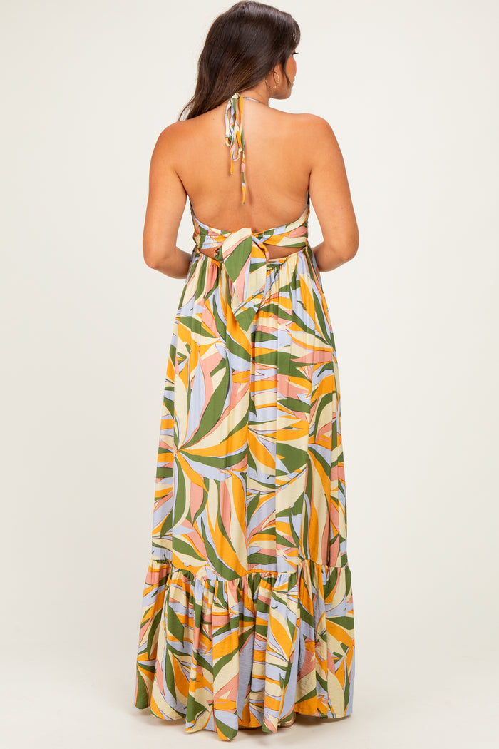 woman wearing a colorful floral print maternity maxi dress with a halter neck and back tie detail