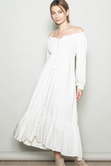 woman wearing a white off-the-shoulder button-up maxi dress with long sleeves and a ruffled hem