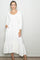 woman wearing a white long sleeve maxi dress with button details and a tiered hem, posing with a slight smile