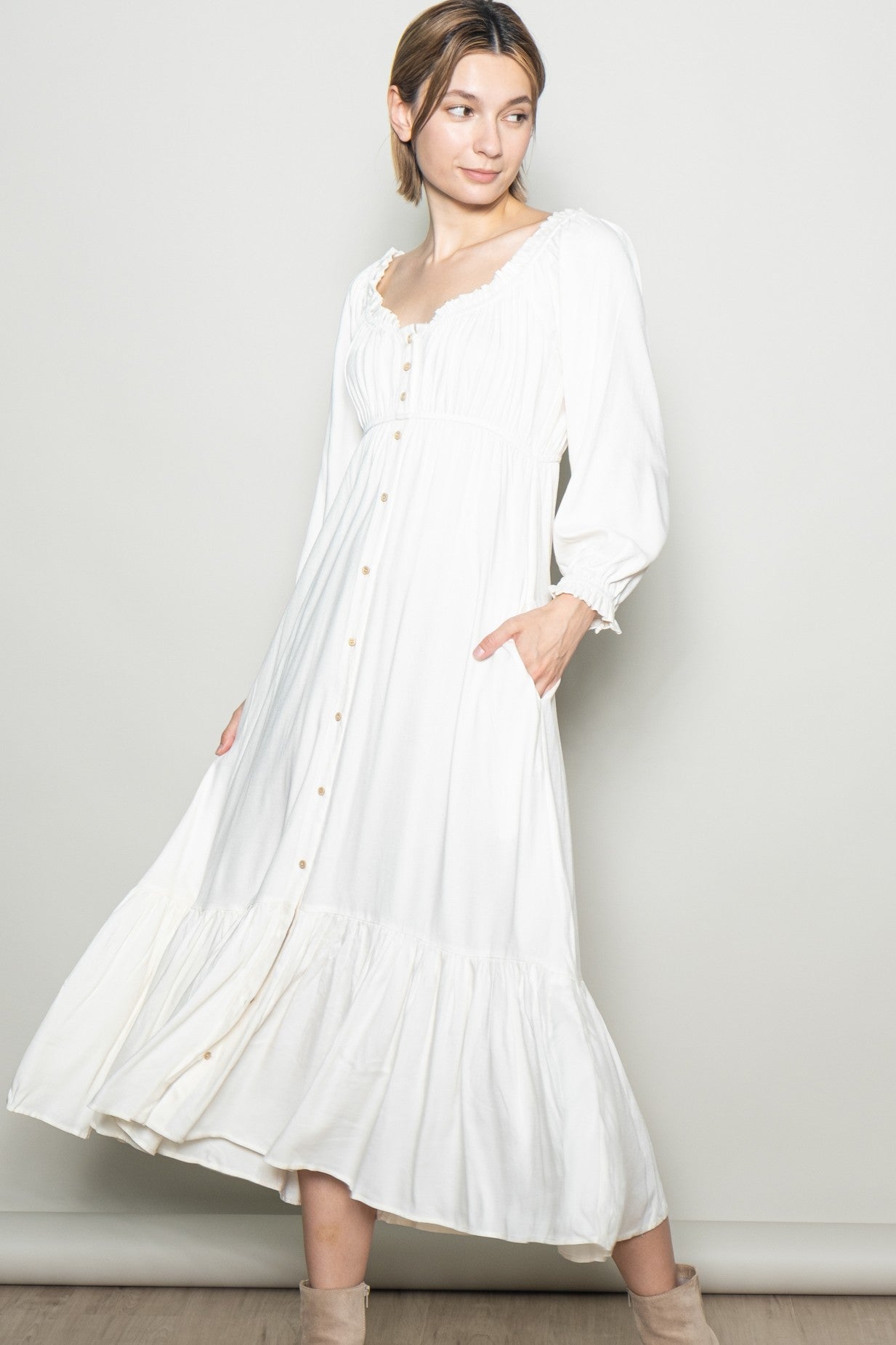 woman wearing a white long sleeve maxi dress with a button-down front and pockets