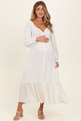 woman wearing a white long sleeve maternity dress with a ruffled hem and buttons, holding her baby bump