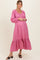 woman wearing a pink maternity dress with long sleeves and ruffled hem, featuring a button-down front