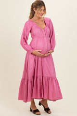 woman wearing a pink maternity maxi dress with buttons and ruffled hem, showing her baby bump