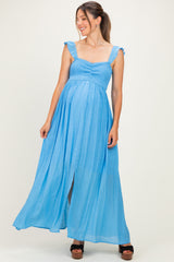 woman wearing a blue maternity maxi dress with ruffled straps and a smocked bodice, showing her baby bump