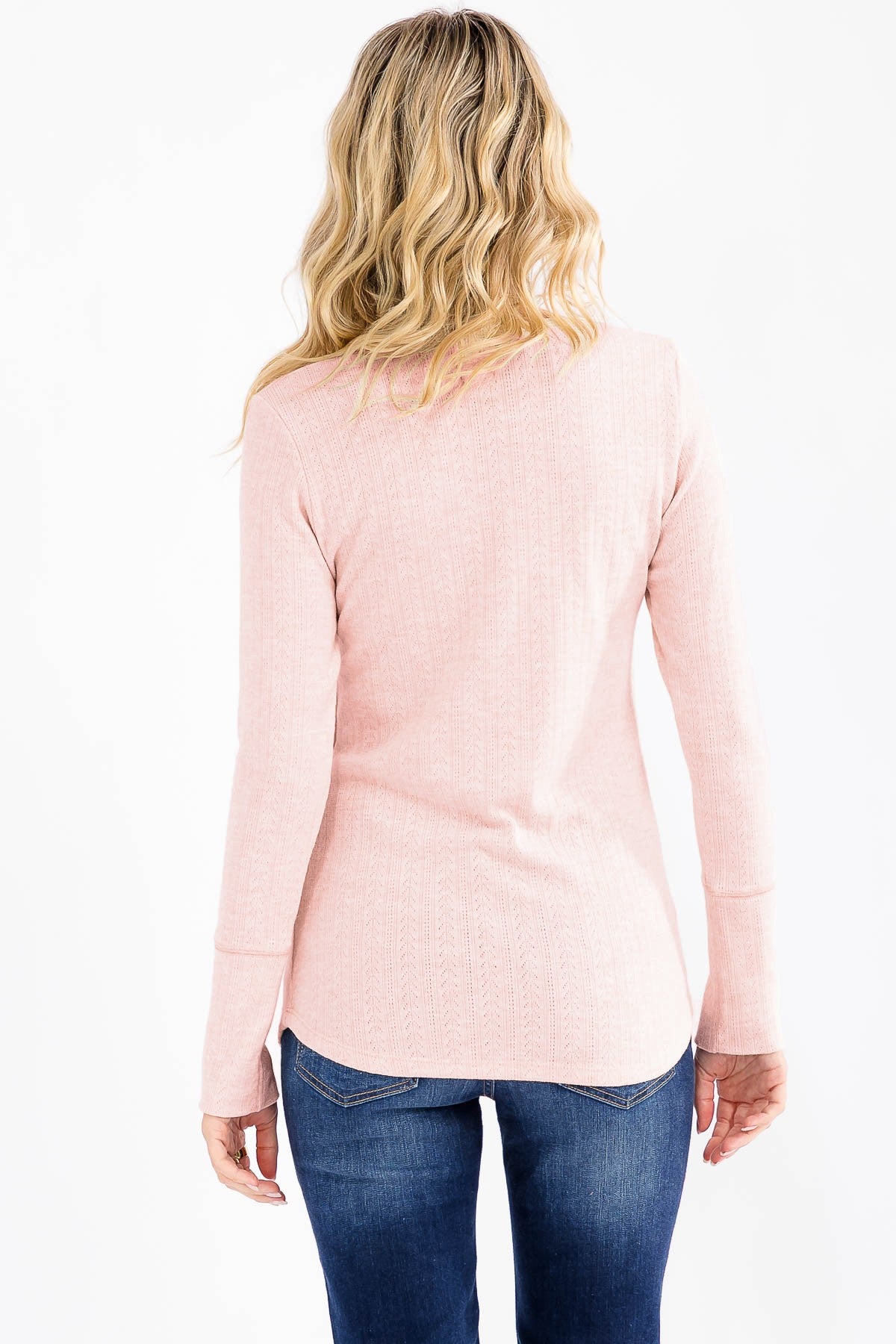 woman wearing a light pink long sleeve top, view from the back, paired with blue jeans