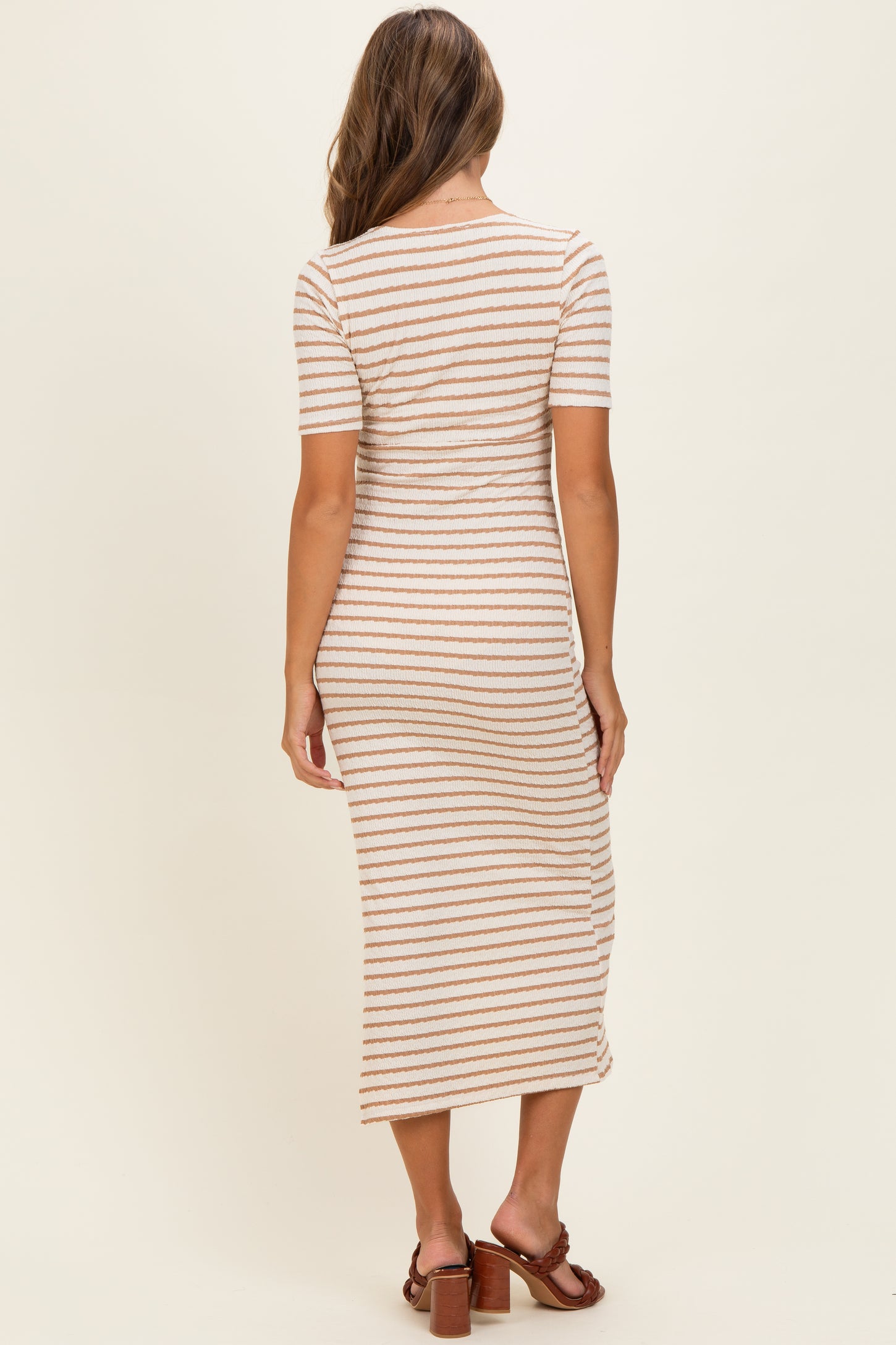 woman wearing a beige and white striped midi dress with short sleeves and a fitted silhouette