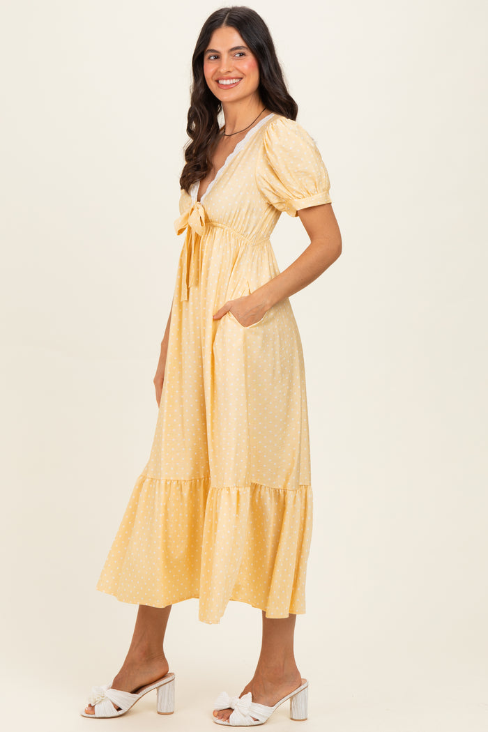 woman wearing a yellow polka dot midi dress with puff sleeves and a tied neckline, featuring side pockets