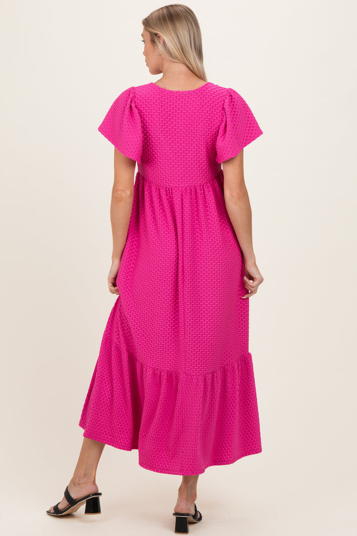 woman wearing a bright pink maternity dress with puff sleeves and a tiered hem, showing the back view