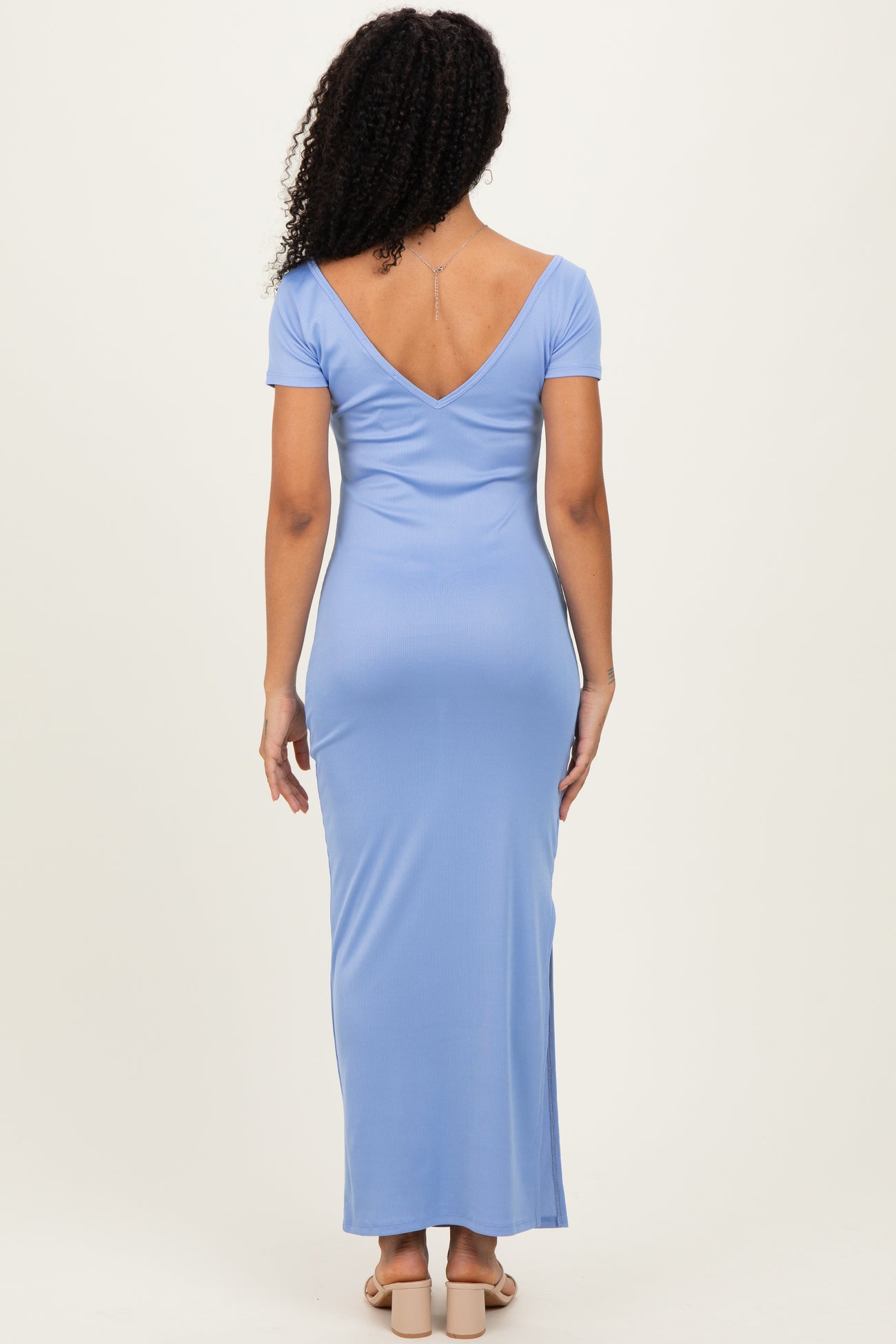 woman wearing a light blue short sleeve maxi dress with a deep v-back, seen from the back