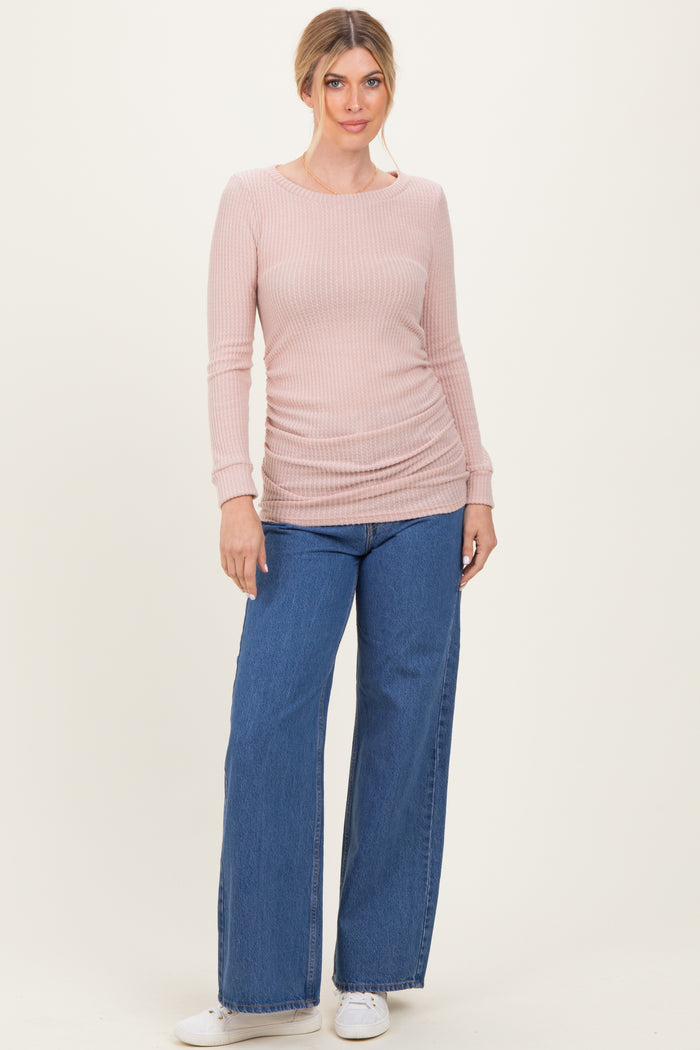 woman wearing a light pink ribbed long sleeve top with side ruching and wide leg denim jeans