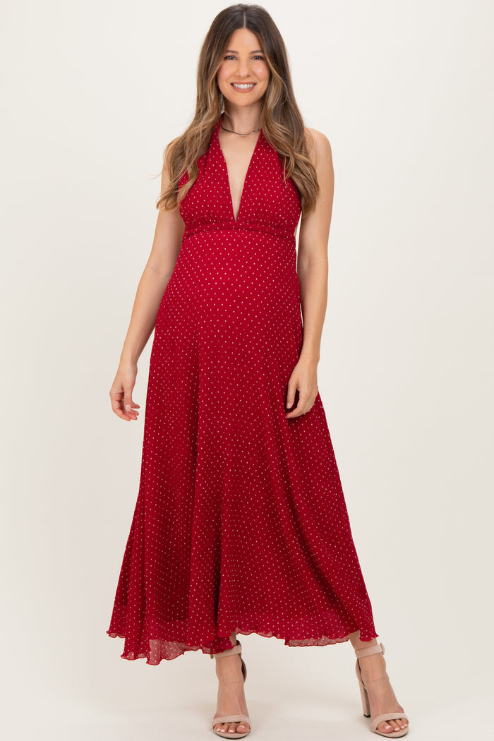 woman wearing a red polka dot maternity dress with a halter neckline and flowing skirt, showcasing her baby bump