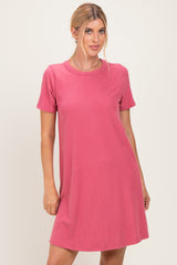 woman wearing a short sleeve ribbed pink dress standing against a neutral background