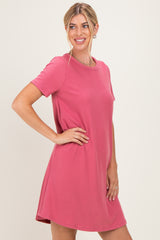 woman wearing a pink short sleeve dress with a relaxed fit and round neckline, standing and smiling
