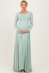 woman wearing a light green long sleeve maternity maxi dress and holding her baby bump
