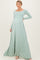 woman wearing a mint green long sleeve maternity maxi dress with a fitted bodice and flowy skirt, showing her baby bump