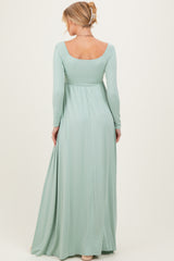 woman wearing a long sleeve mint green maternity maxi dress, showing her back and flowing fabric