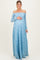 woman wearing a light blue off-the-shoulder lace maternity gown with long sleeves and cradling her baby bump