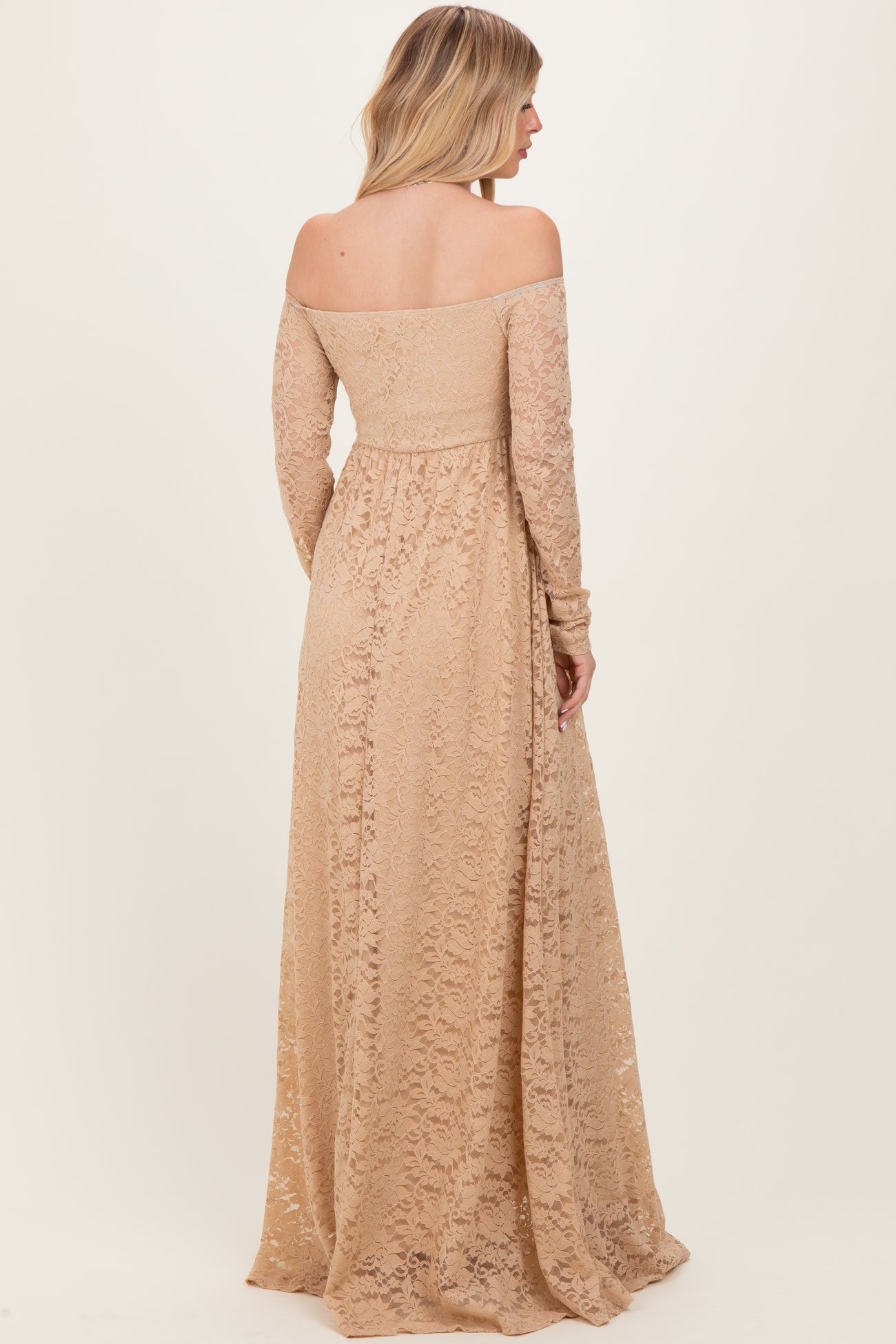 woman wearing a long off-the-shoulder nude lace dress with long sleeves and a flowing skirt from the back