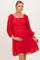 woman wearing a red maternity dress with a smocked bodice and puff sleeves, holding her baby bump