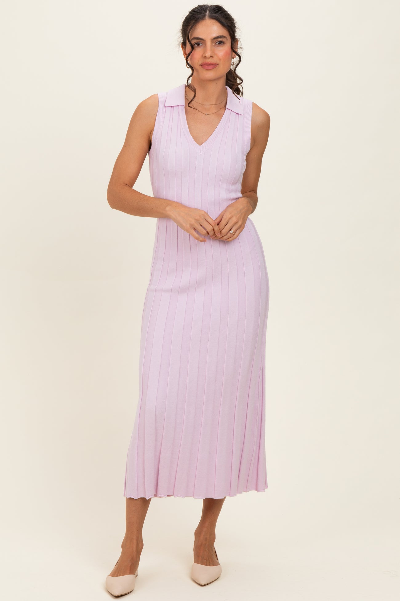 woman wearing a light pink sleeveless ribbed midi dress with a v-neck and collar, styled with neutral pointed-toe heels