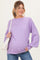 woman wearing a lavender maternity sweater with balloon sleeves and a visible baby bump, holding a white handbag