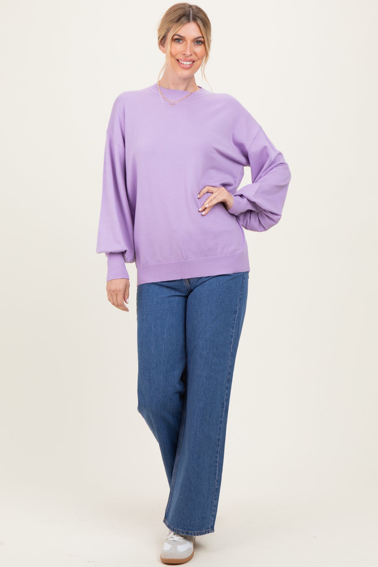 woman wearing a lavender oversized sweater and wide-leg blue jeans, styled with white sneakers